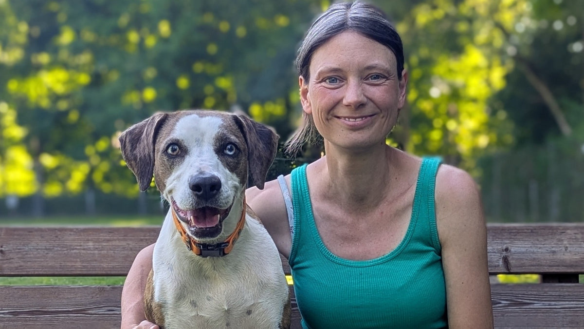 Sarah Mikulla mit einem großen Hund auf einer Parkbank